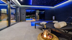 A modern spa area with a pool, a massage table, and a bottle of champagne. - Villa Le Maris by Villas Guide (Klanice)