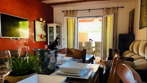 A dining area with a table set for two, a television mounted on the wall, and a view of the outside. - Villas 2 meet Estamarell – Private Oasis in Mallorca’s Natural Landscape (Romàntica)