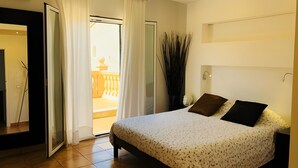 A bedroom with a bed, a mirror, a door leading to a balcony, and a potted plant. - Villas 2 meet Estamarell – Private Oasis in Mallorca’s Natural Landscape (Romàntica)