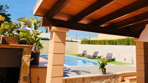 A covered outdoor area with a pool, lounge chairs, and potted plants. - Villas 2 meet Estamarell – Private Oasis in Mallorca’s Natural Landscape (Romàntica)