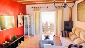 A living room with a TV, a cabinet, a sofa, a table, and a fireplace. - Villas 2 meet Estamarell – Private Oasis in Mallorca’s Natural Landscape (Romàntica)