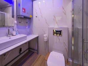 Ein modernes Badezimmer mit Waschtisch aus Marmor, Toilette und einer Duschkabine aus Glas.