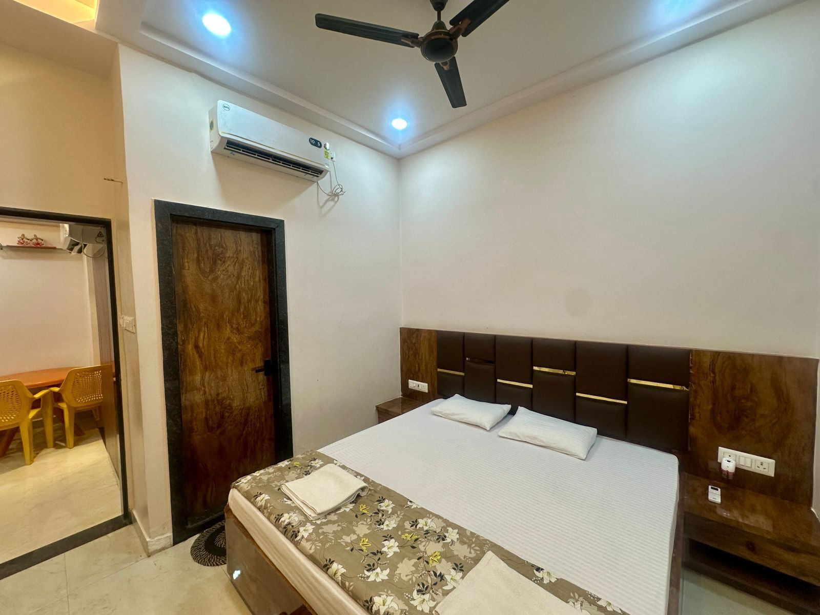 Een slaapkamer met een bed, een plafondventilator, een airconditioning en een houten deur.