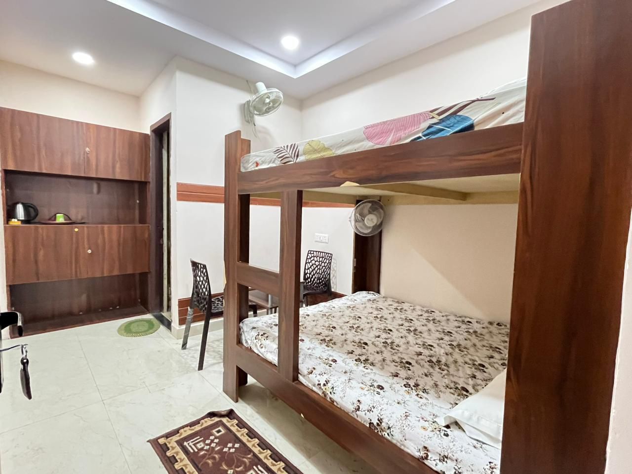 A room with a bunk bed, a desk, a chair, and a small cabinet.