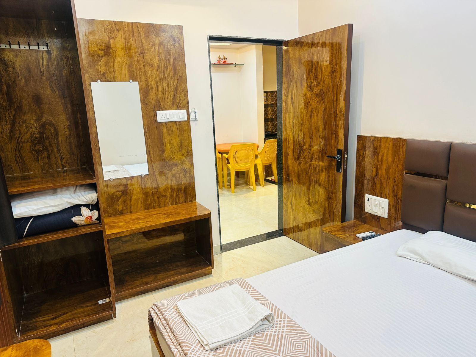 A hotel room with a bed, a wardrobe with a mirror, and a seating area with a table and chairs.