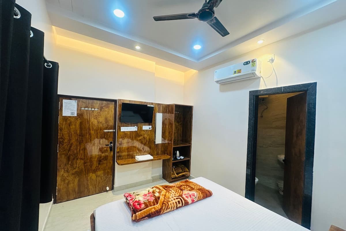 A bedroom with a bed, a ceiling fan, a TV, and a wardrobe.