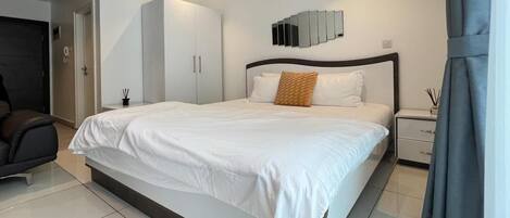 Quarto moderno com uma cama grande, um guarda-roupa, uma mesinha de cabeceira e um espelho na parede.
