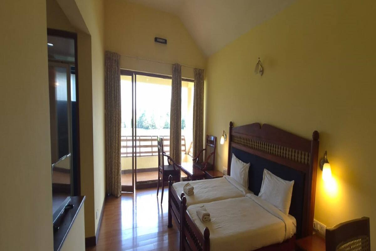 A hotel room with two beds, a balcony, and a view of the outdoors.