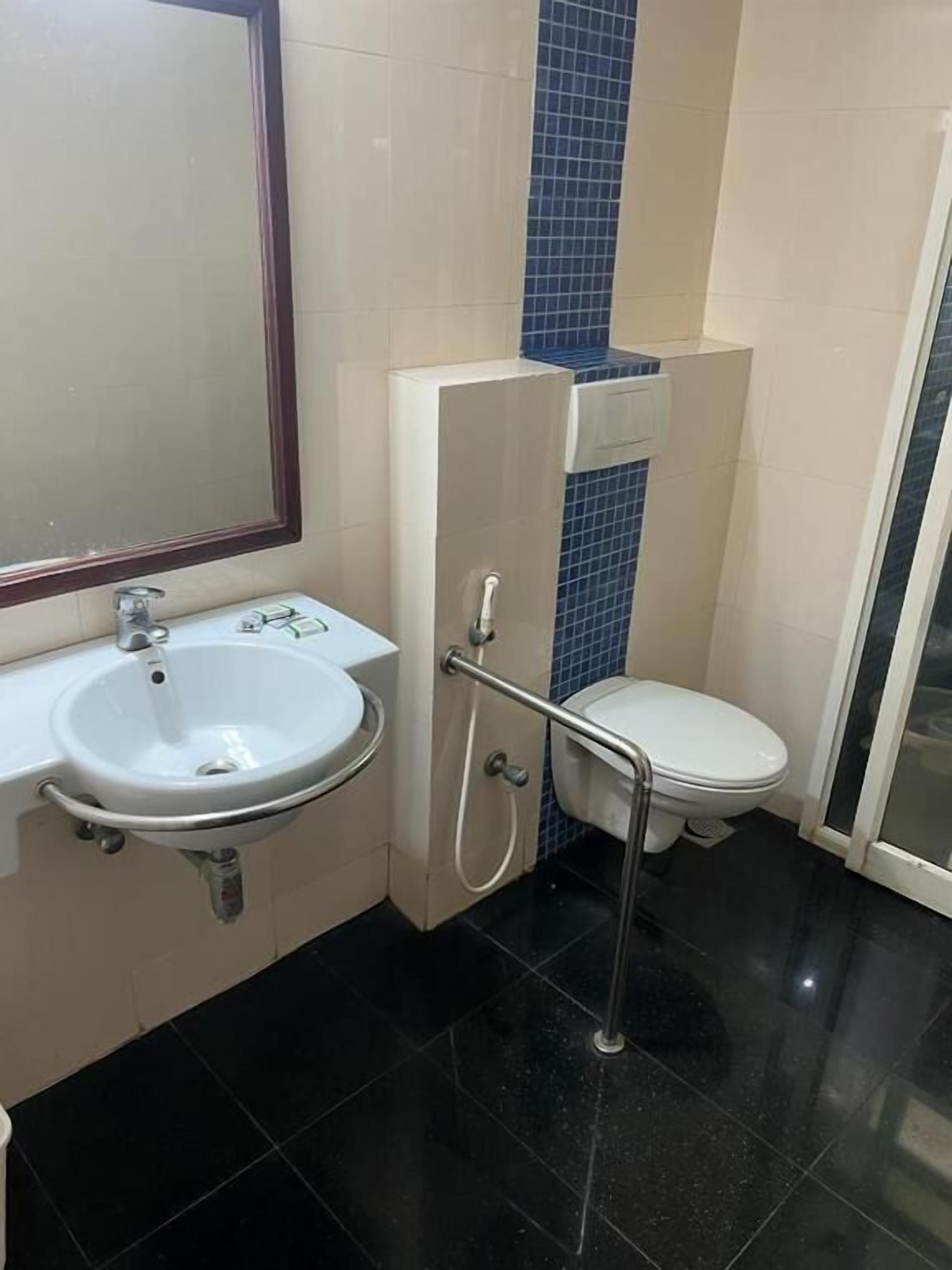 A bathroom with a white sink, a mirror, a toilet, and a shower area.