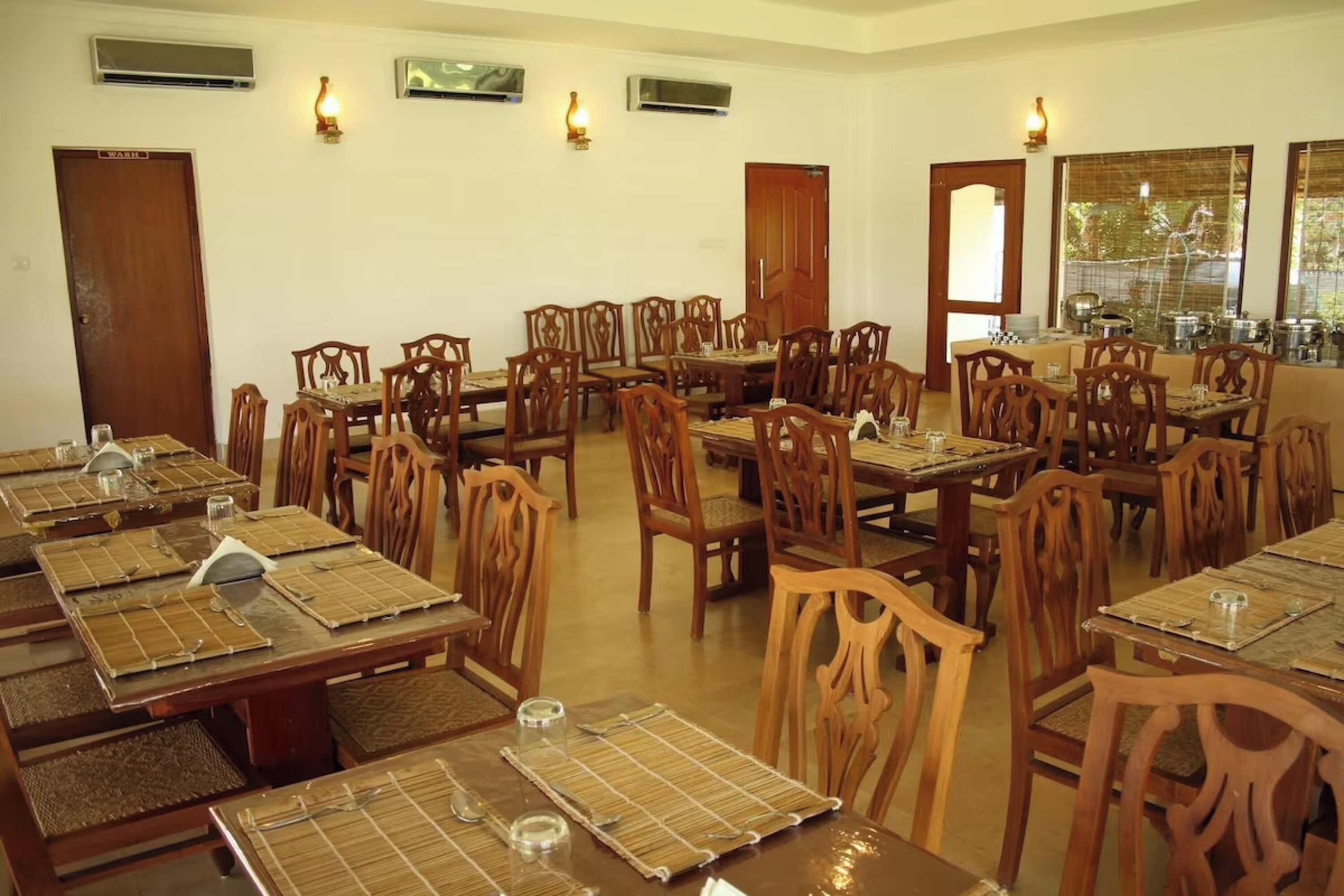 A dining area with multiple wooden tables and chairs, arranged in a spacious layout.
