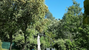 A garden with a paved walkway, outdoor seating, and a variety of plants. - Cabanon provençal: the lezards (sillans la cascade)