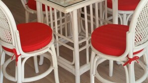 A dining area with a glass-top table, white chairs with red cushions, and a wooden bowl with red apples. - Cabanon provençal: the lezards (sillans la cascade)