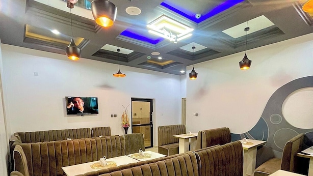 Ein Restaurant mit Sitzelementen, einem Flachbildfernseher und modernen Leuchten.