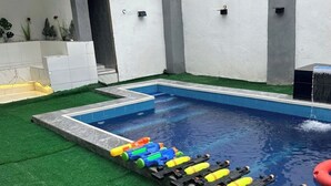 Ein Schwimmbecken mit Kunstgrasanlage und einer Wasserrutsche mit bunten Wasserspielen.