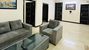 Un salón amplio con dos sofás grises, una mesa de centro de cristal y un ventilador de techo.