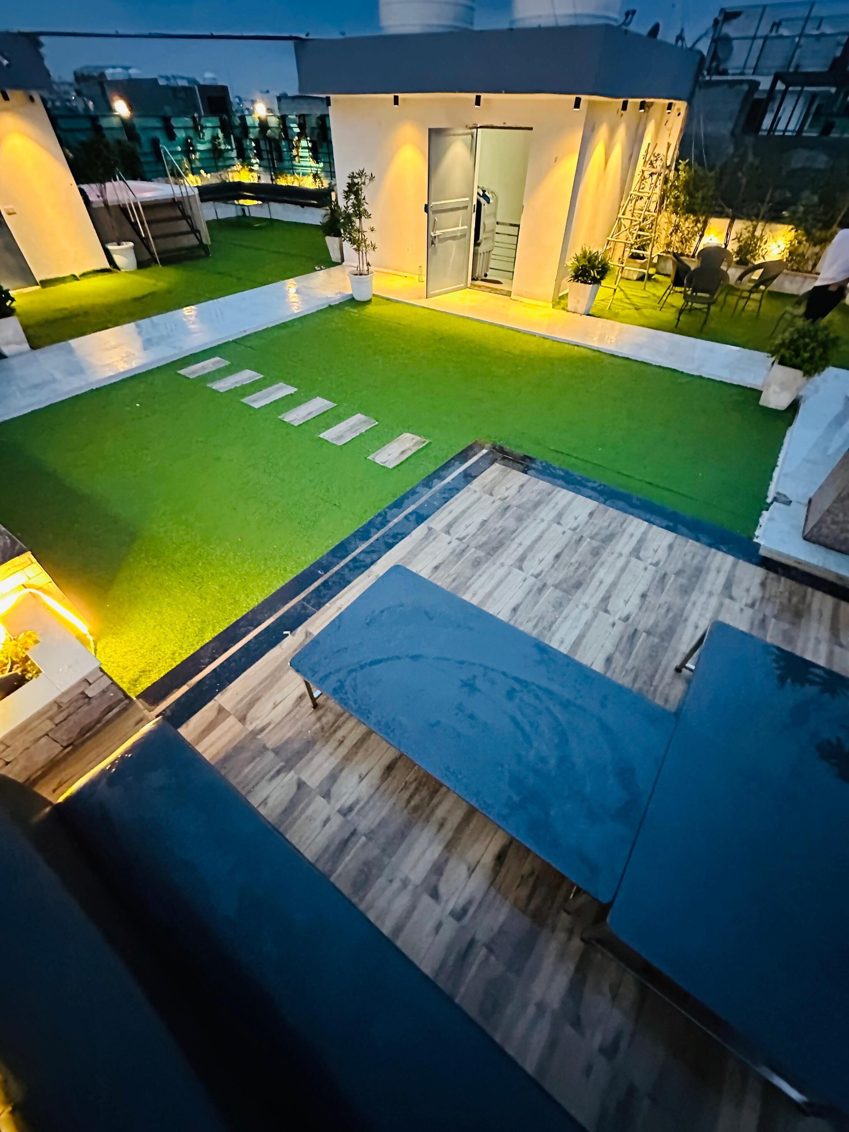 A rooftop terrace with artificial grass, a wooden deck, and a seating area.