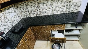 Una cocina con encimera negra, salpicadero de mármol y un fregadero con escurreplatos.
