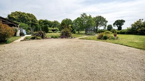 A gravel driveway leading to a house with a fenced yard and various plants. - Holiday Home "Gîte Les Hortensias with Pool" – Private Pool, Wi-Fi & Air Conditioning (Trébédan)