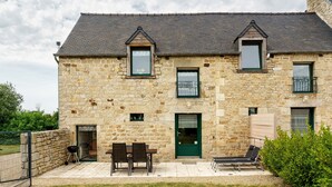 A stone building with a patio, a dining table, and outdoor seating. - Holiday Home "Gîte Les Hortensias with Pool" – Private Pool, Wi-Fi & Air Conditioning (Trébédan)
