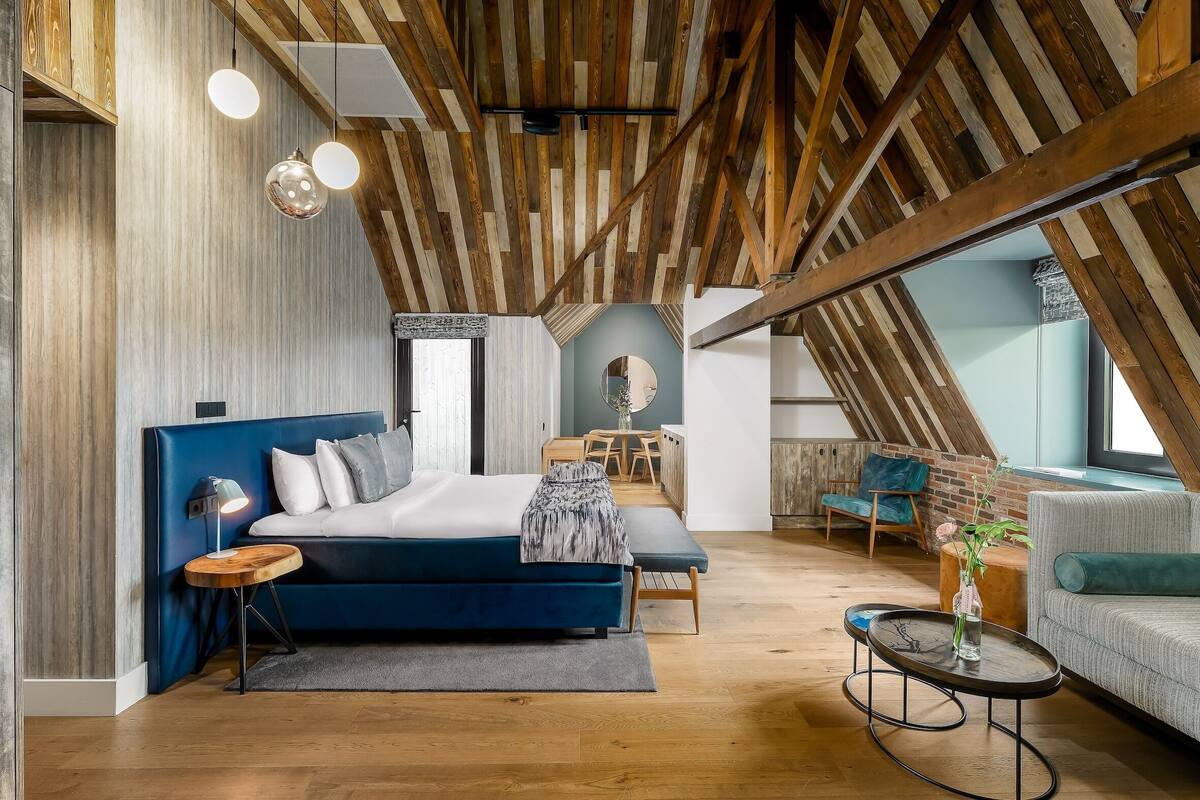 A modern loft bedroom with a large bed, a desk, and a seating area.