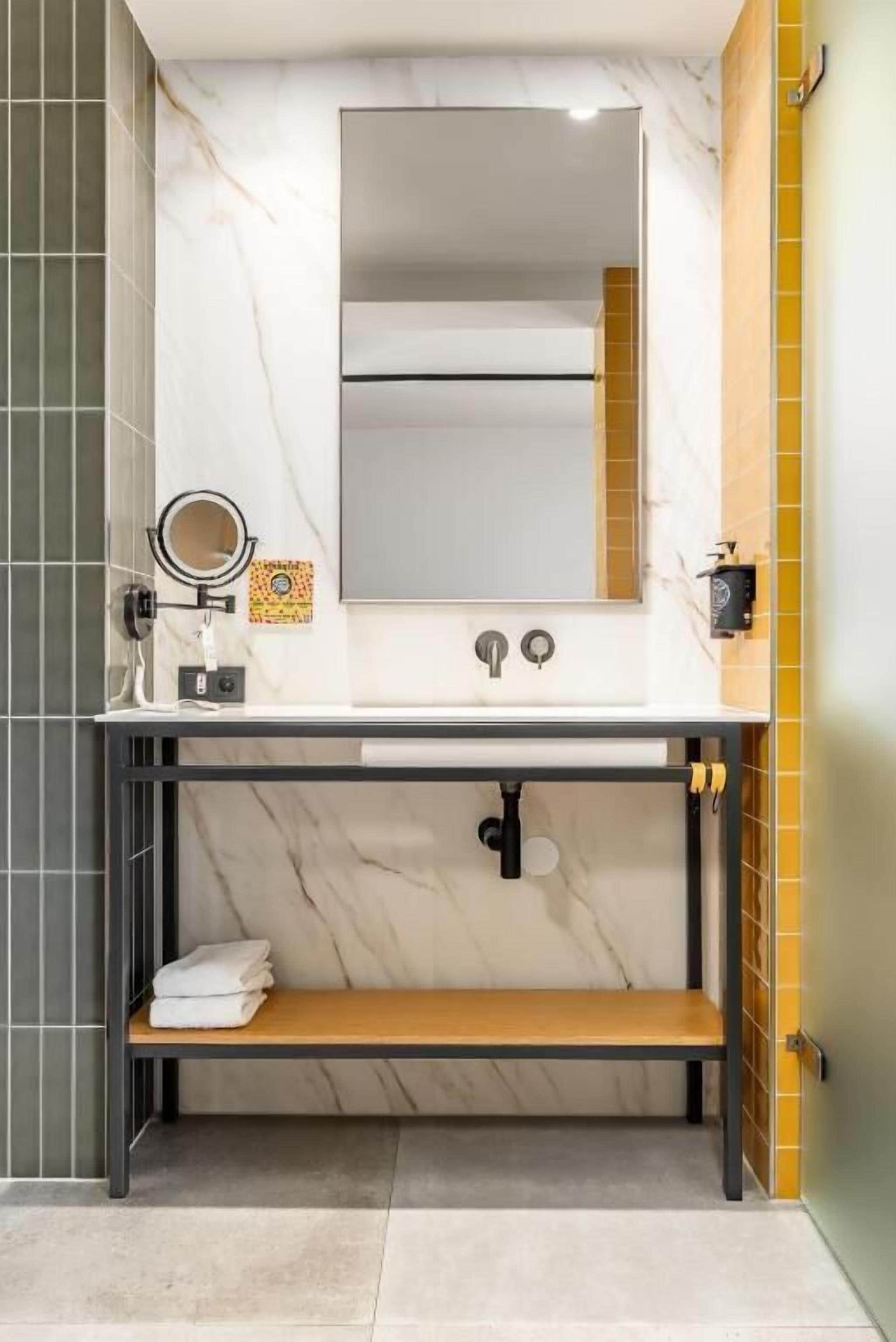 Een badkamer met een marmeren wastafel, een spiegel, een handdoekhouder en een plank.