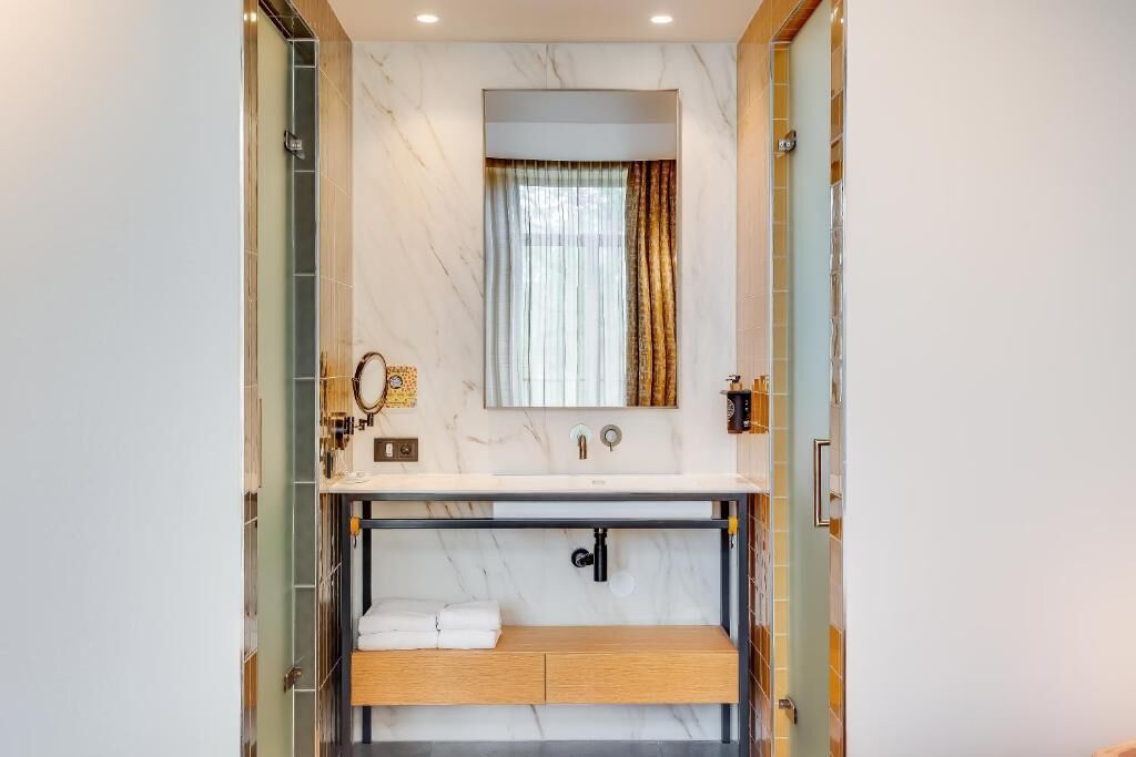A modern bathroom with a marble vanity, a towel rack, and a shower area.