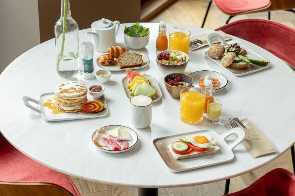 Una mesa de desayuno con varios platos, como panqueques, huevos y fruta.
