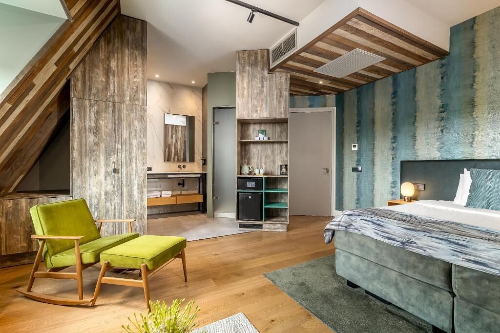 Un dormitorio moderno con una cama grande, una silla verde, un sillón mecedor de madera y un armario empotrado.