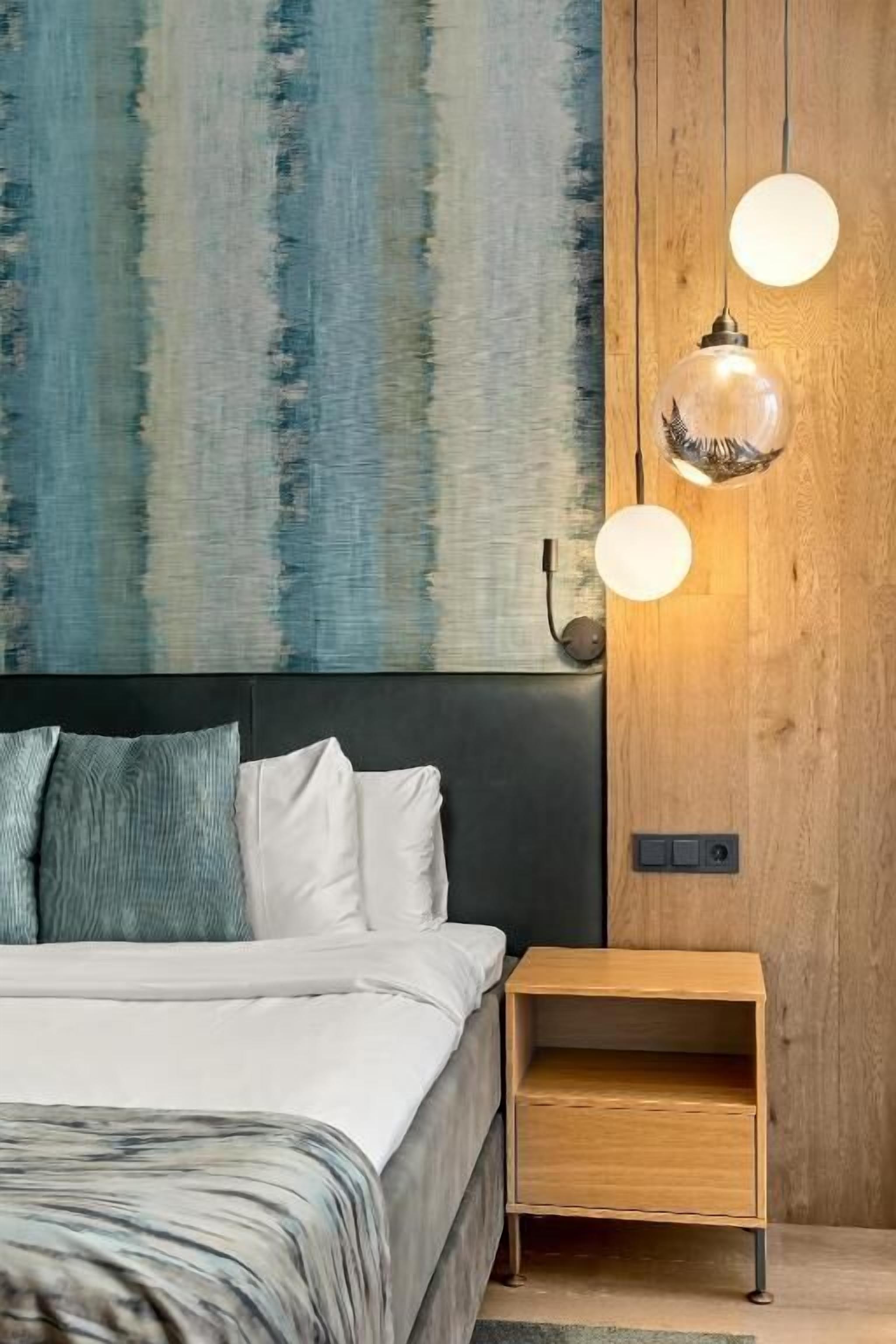 A bedroom with a bed, a wooden nightstand, and a wall-mounted light fixture.