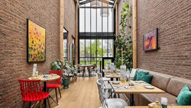 Un restaurante con paredes de ladrillo, mesas de madera y sillas rojas.