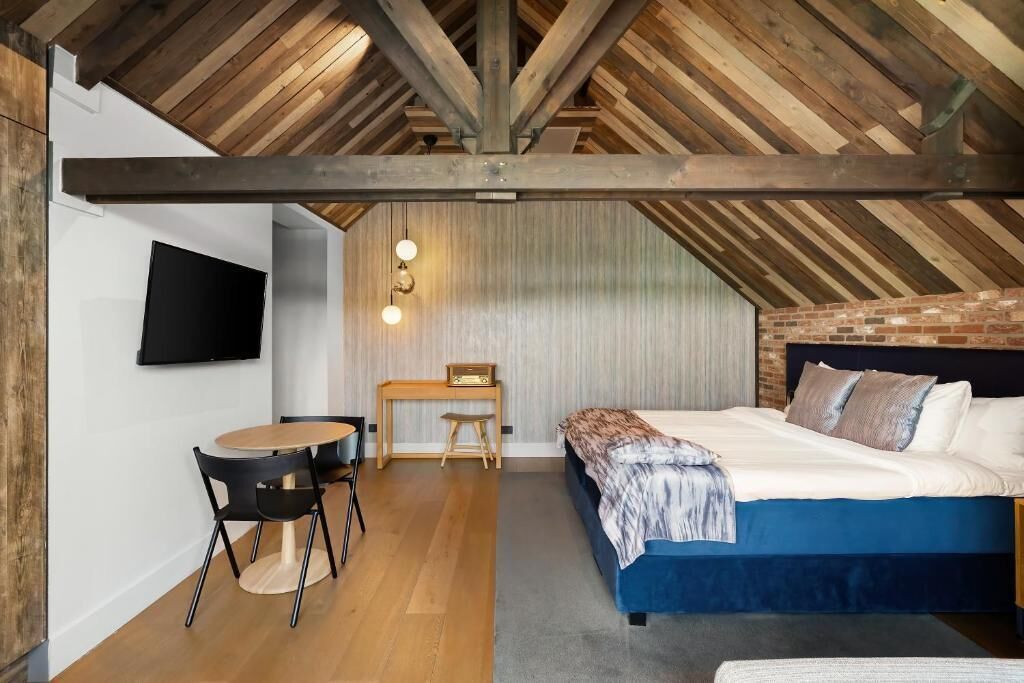 A bedroom with a sloped ceiling, a bed, a desk, and a chair.