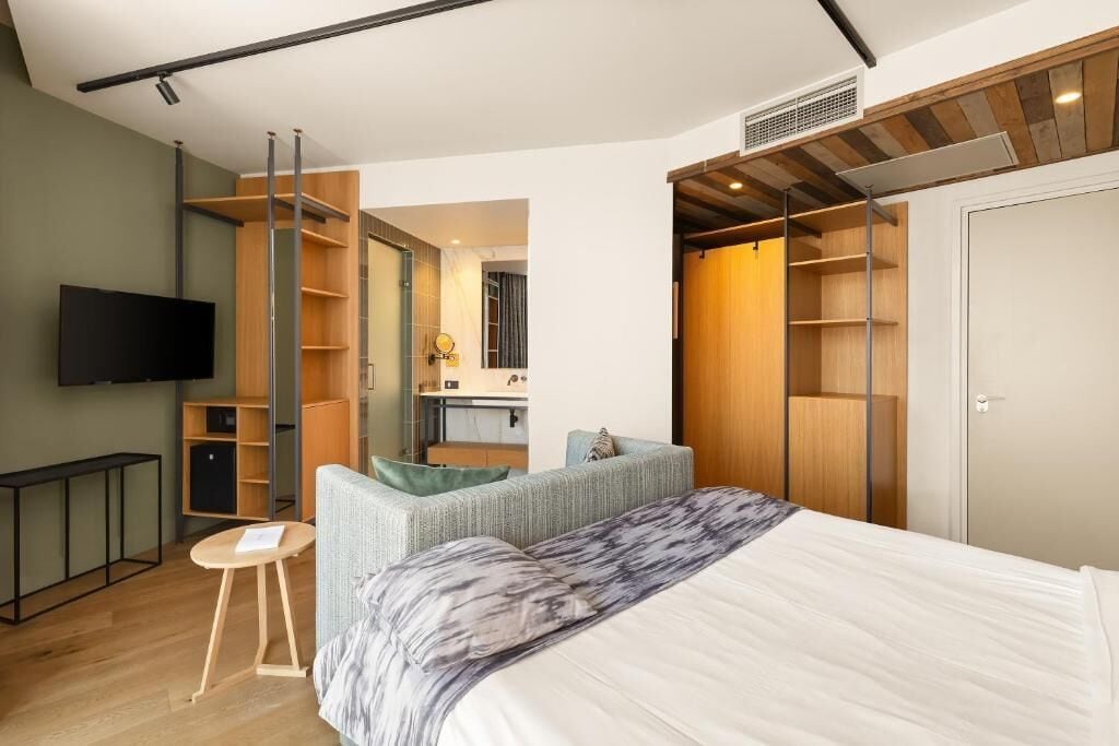 Une chambre moderne équipée d’un lit, d’une télévision, d’un bureau et de rangements intégrés.