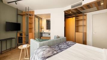 A modern bedroom with a bed, a TV, a desk, and built-in storage.
