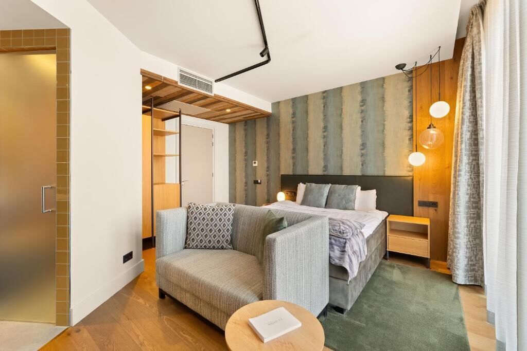 Een moderne hotelkamer met een bed, een bank, een klein tafeltje en een inloopkast.