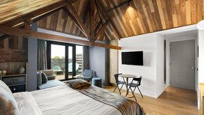 Un dormitorio con una cama grande, un televisor montado en la pared y una zona de comedor con mesa y sillas.