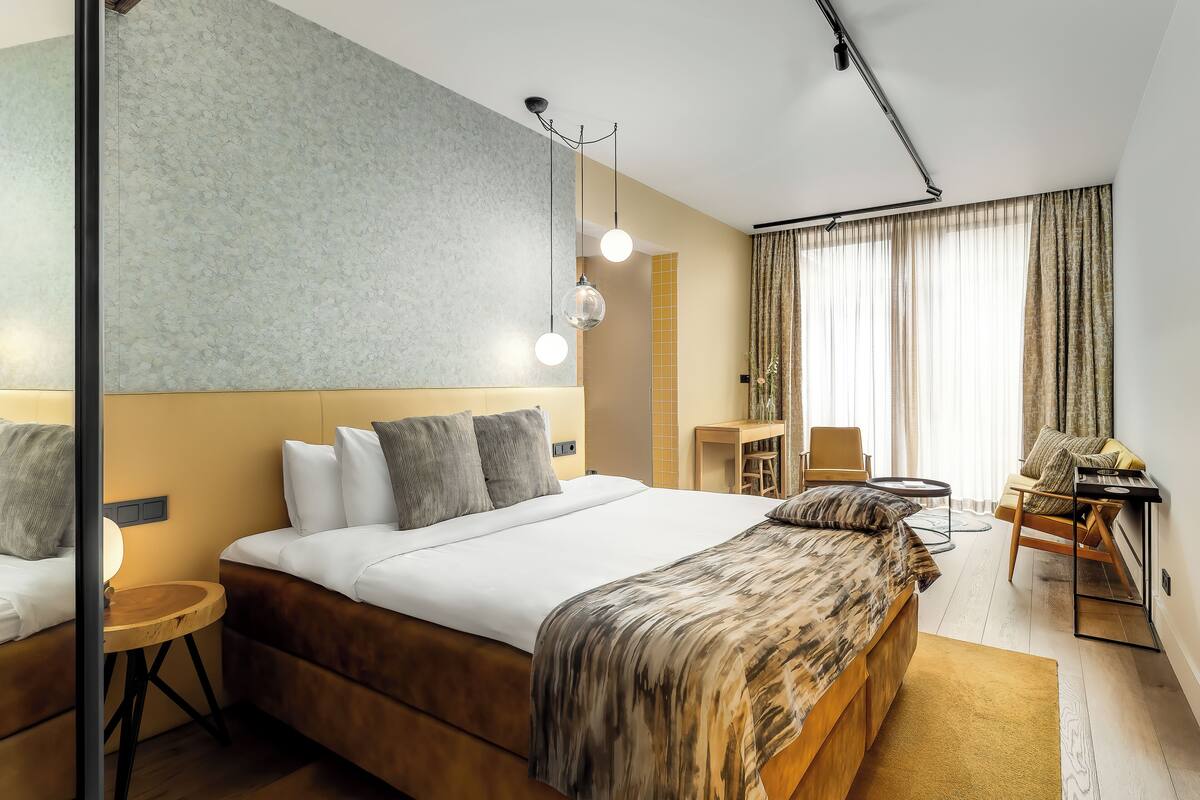 A modern hotel room with a large bed, a desk, and a chair.