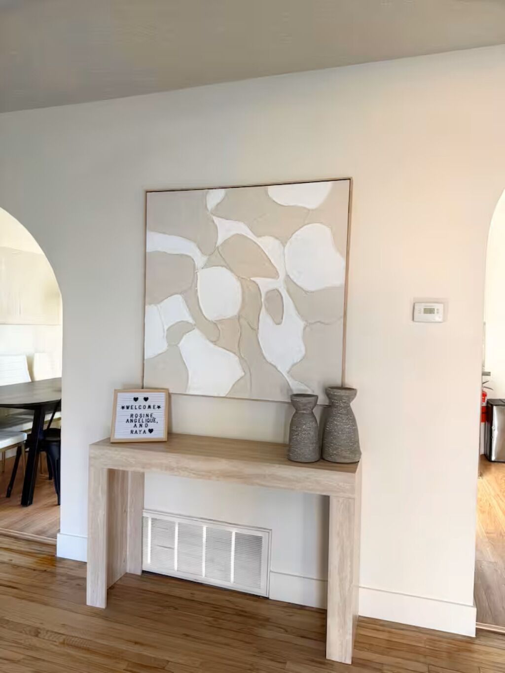 Un interior moderno con una consola, arte abstracto y un cartel de bienvenida.