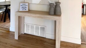 Um interior moderno com um console, obra de arte abstrata e uma placa de boas-vindas.