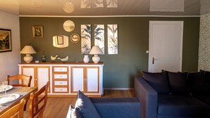 A dining area with a wooden table and chairs, a cabinet with drawers, and a sofa.