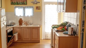 A kitchen with wooden cabinets, a sink, a stove, and a window with curtains.