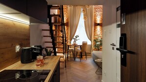 A modern kitchen with a wooden countertop, a coffee machine, and a kettle. There is a dining area with a table and chairs, and a brick wall in the background. - L23 Boutique by Downtown Apartments (Kraków)