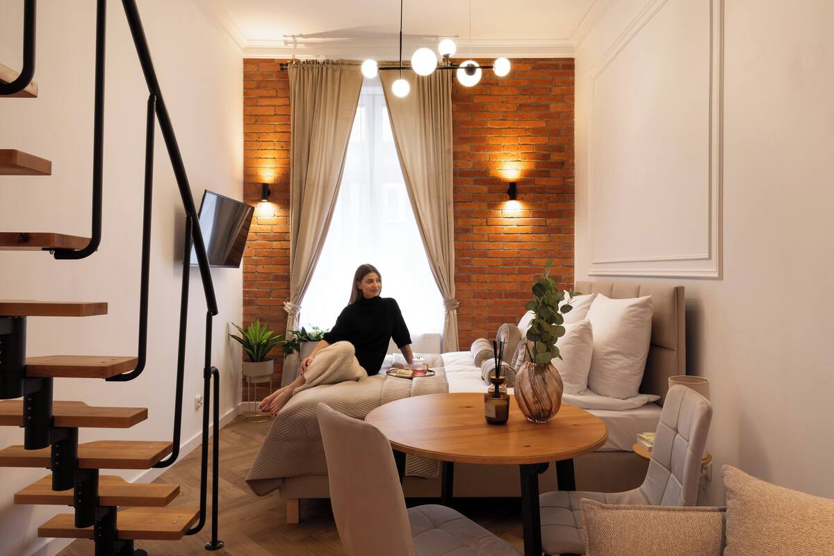 Una sala de estar moderna con pared de ladrillo, un sofá, una mesa de centro y un televisor montado en la pared.