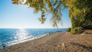 A pebbled beach with a clear view of the sea and a rocky cliff. - Sunday Resort Rugen Junior Suite Manor House (Sagard)