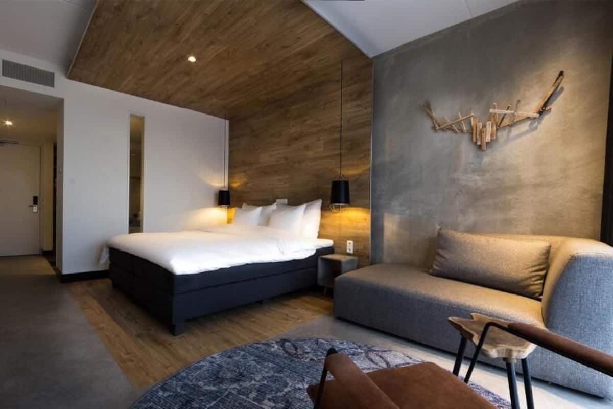 Ein modernes Hotelzimmer mit einem großen Bett, einer Couch und einem einzigartigen Wandbild.