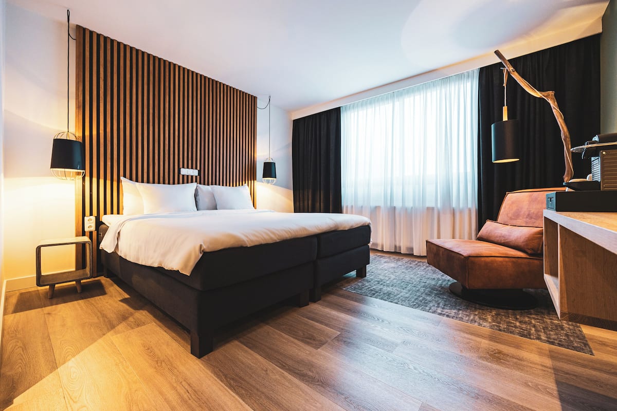 Ein modernes Hotelzimmer mit einem großen Bett, einem Schreibtisch und einem Stuhl.
