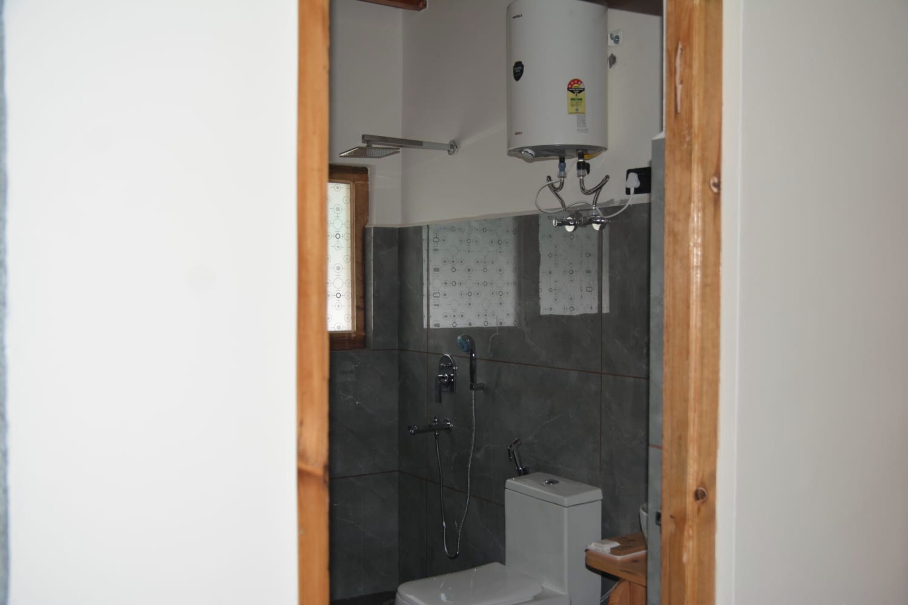 A bathroom with a shower, toilet, and a water heater mounted on the wall.