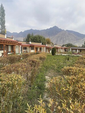 A row of traditional-style buildings with wooden structures and red roofs, set against a backdrop of mountains.