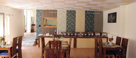 A dining area with wooden tables and chairs, a buffet counter, and a mirror on the wall.