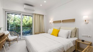 A bedroom with a large bed, a balcony with wicker furniture, and a view of greenery. - Lemon pie by halu! Charming studio next to Aristotelous Square (Thessaloniki)