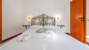 Ett hotellrum med en stor säng, två sängbord, en trädörr och en vit vägg.